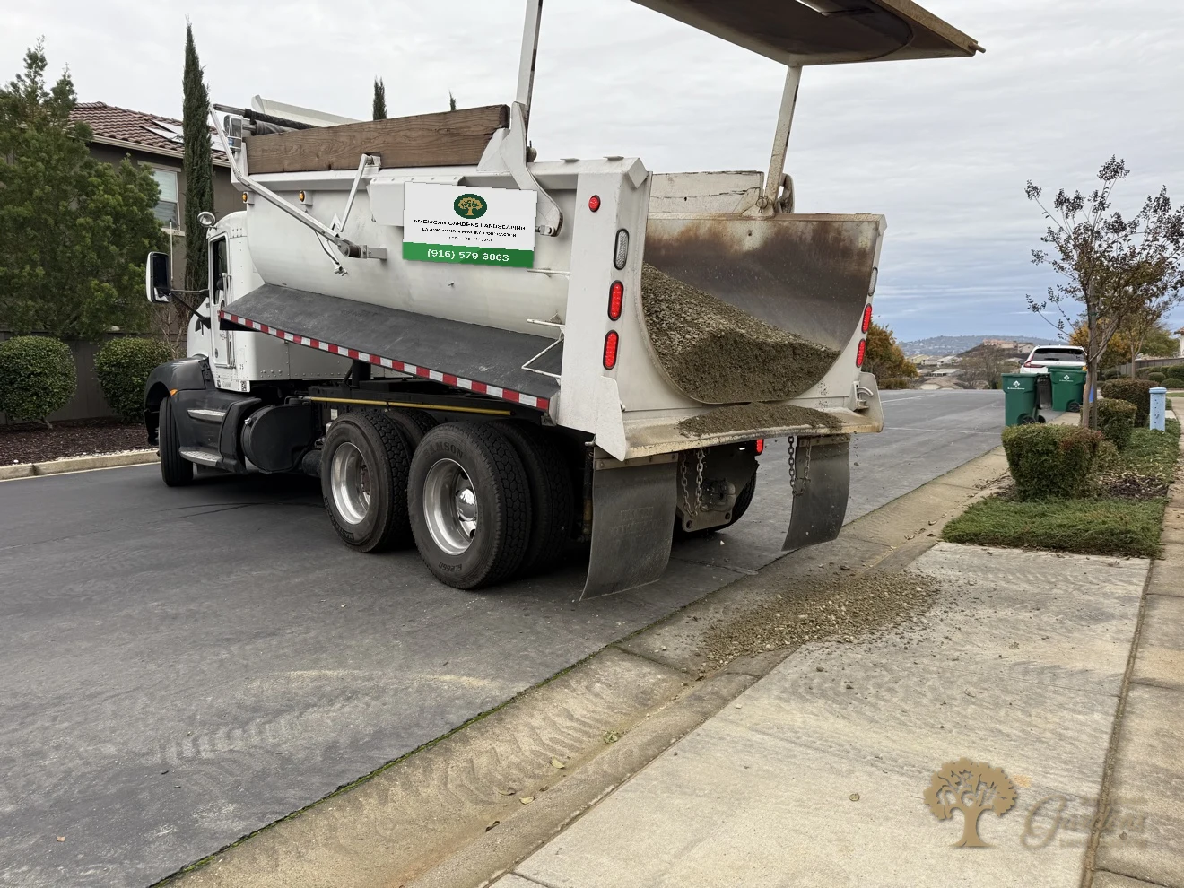 Dump truck delivering base rock to the street for a new paver patio in El Dorado Hills, by American Gardens Landscaping.