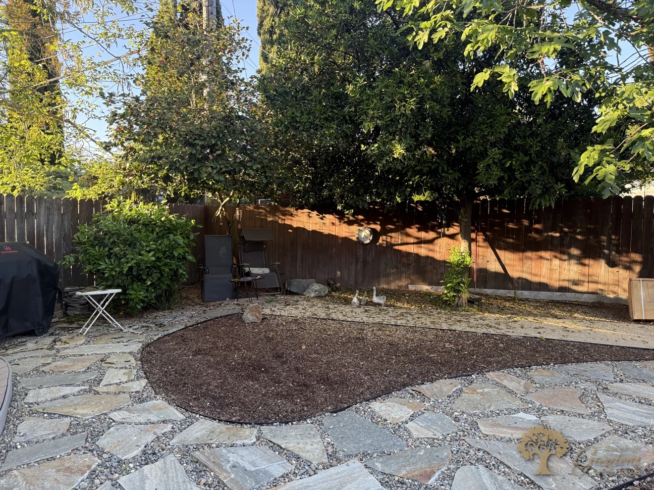 Flagstone patio with gravel joints around a mulched planting bed in El Dorado Hills, built by American Gardens Landscaping