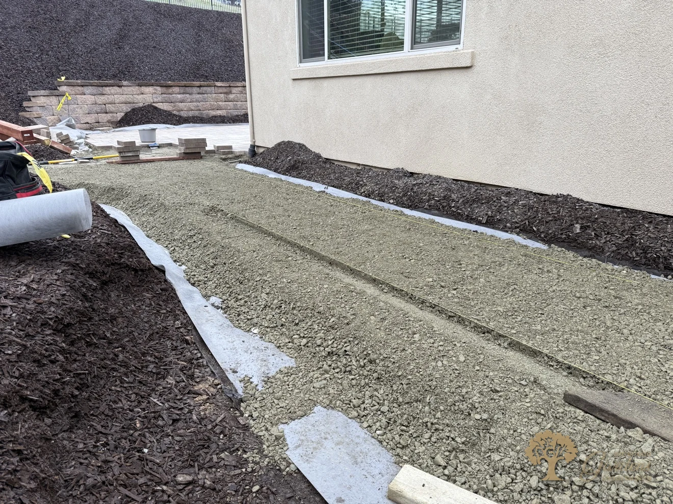 Freshly screeded sand bed over filter fabric, leveled and ready for pavers, below the block retaining wall in El Dorado Hills, by American Gardens Landscaping.