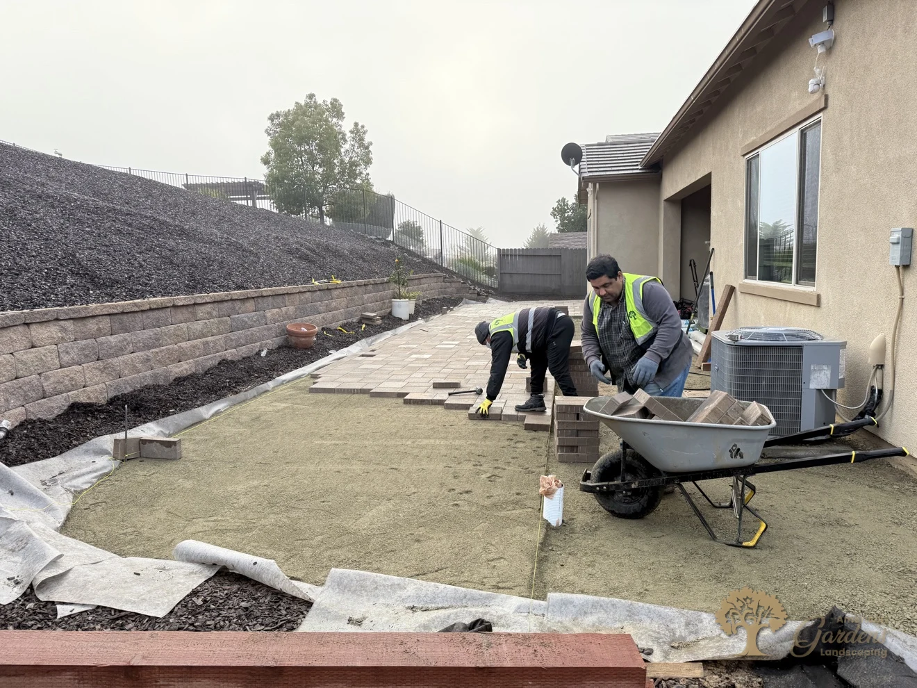 Crew laying the paver field piece by piece on the leveled sand bed beside the house in El Dorado Hills, by American Gardens Landscaping.