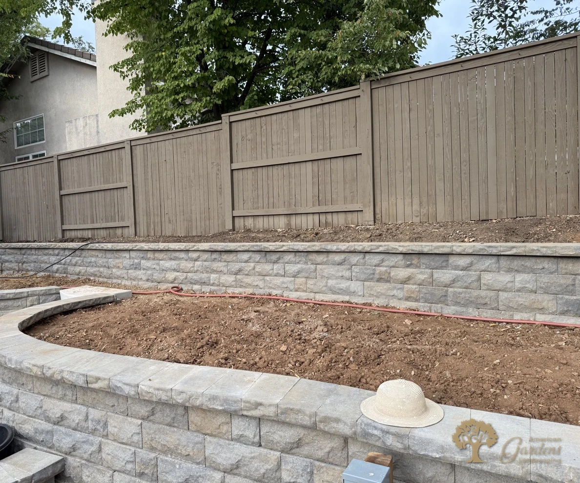 Finished stained wood fence above terraced block retaining walls in a Serrano backyard in El Dorado Hills, by American Gardens Landscaping.