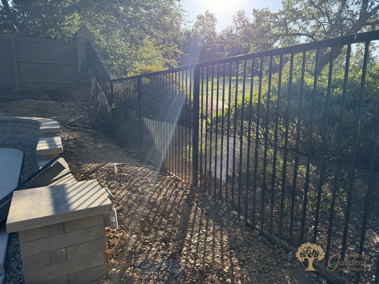 Black metal fence running down a sloped Serrano backyard in El Dorado Hills, by American Gardens Landscaping.