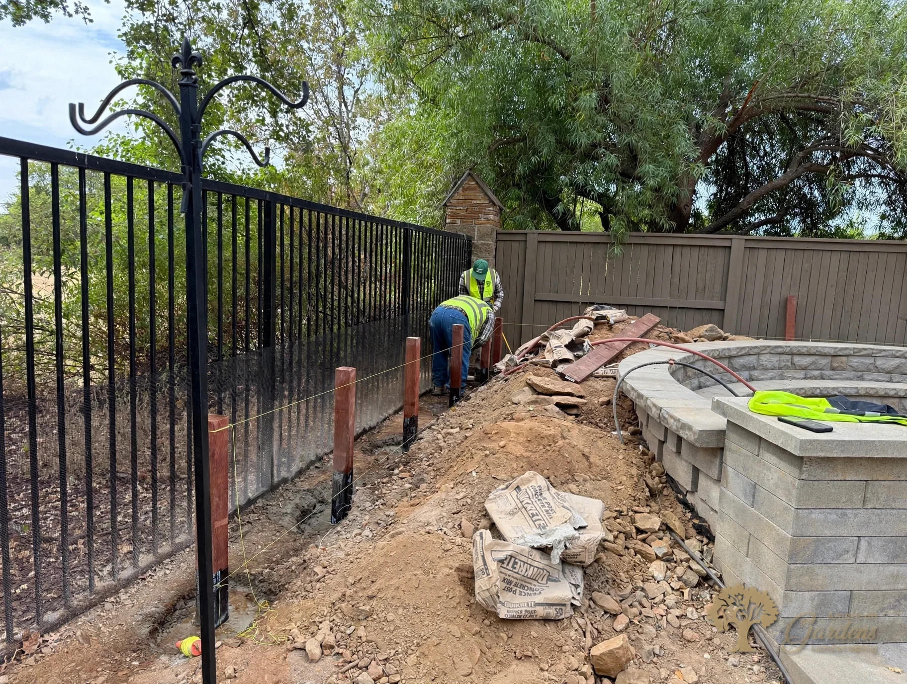 Crew setting fence posts on a string line for a straight run along a black metal fence in Serrano, El Dorado Hills, by American Gardens Landscaping.