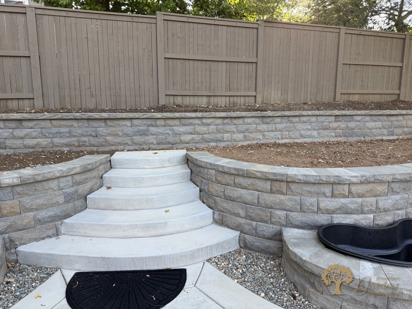 Curved concrete steps climbing between terraced block retaining walls in a Serrano backyard in El Dorado Hills, by American Gardens Landscaping.