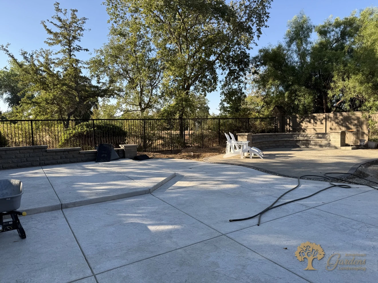 Wide stamped-concrete patio with a black metal view fence in a Serrano backyard in El Dorado Hills, by American Gardens Landscaping.