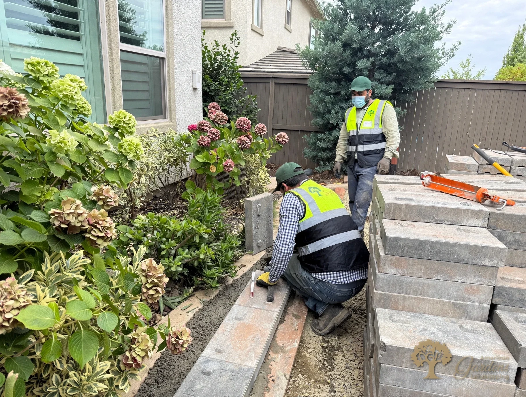American Gardens Landscaping crew setting the first course of a raised planter bed on its footing beside the house in a Serrano backyard in El Dorado Hills.