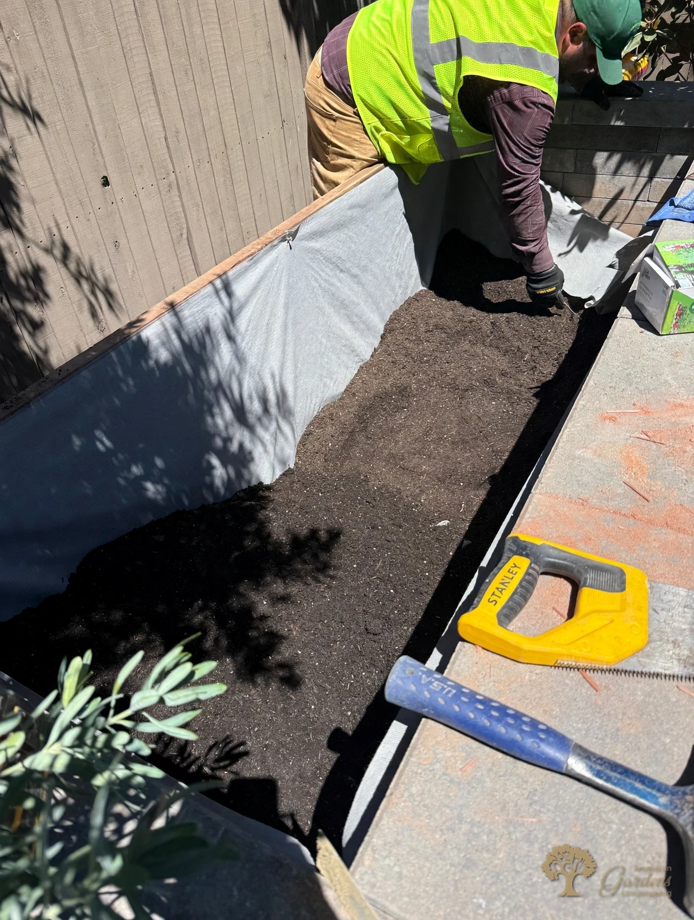 American Gardens Landscaping crew member lining a raised planter bed with filter fabric before the soil goes in, in a Serrano backyard in El Dorado Hills.