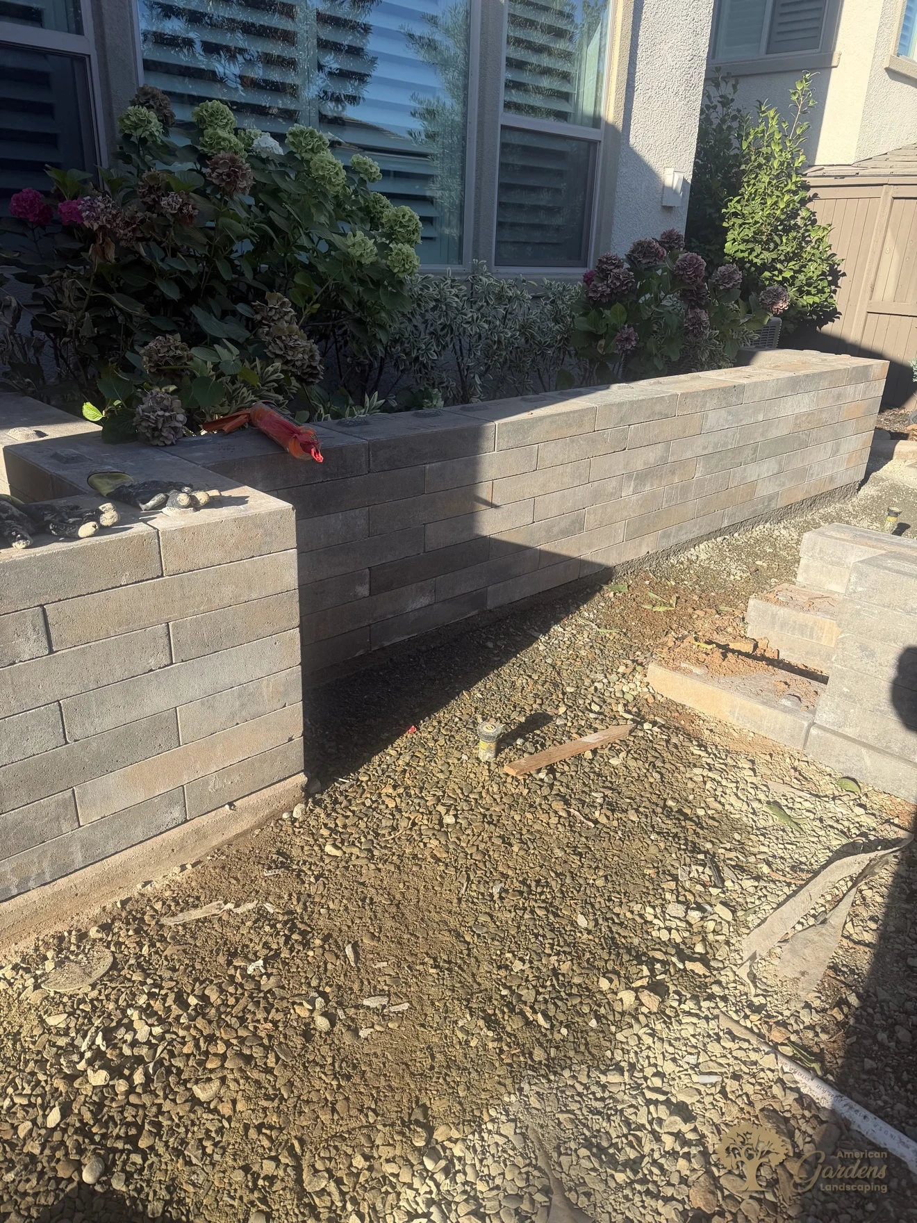 Finished raised planter beds with capstones along the house in a Serrano backyard in El Dorado Hills, by American Gardens Landscaping.