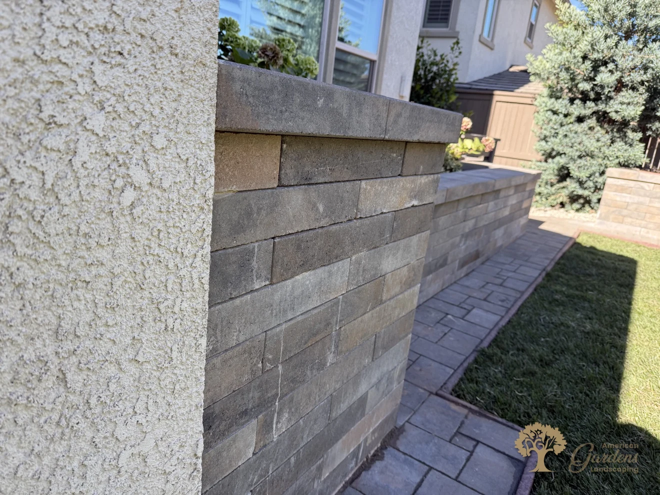 Close-up of the planter wall corner where it meets the house — tight block courses and a clean capstone line above the paver walkway in El Dorado Hills, by American Gardens Landscaping.