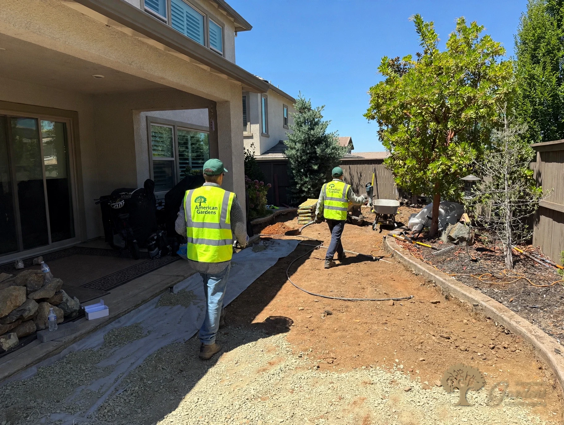 American Gardens Landscaping crew laying filter fabric and gravel base for a new paver walkway beside the covered patio in El Dorado Hills.