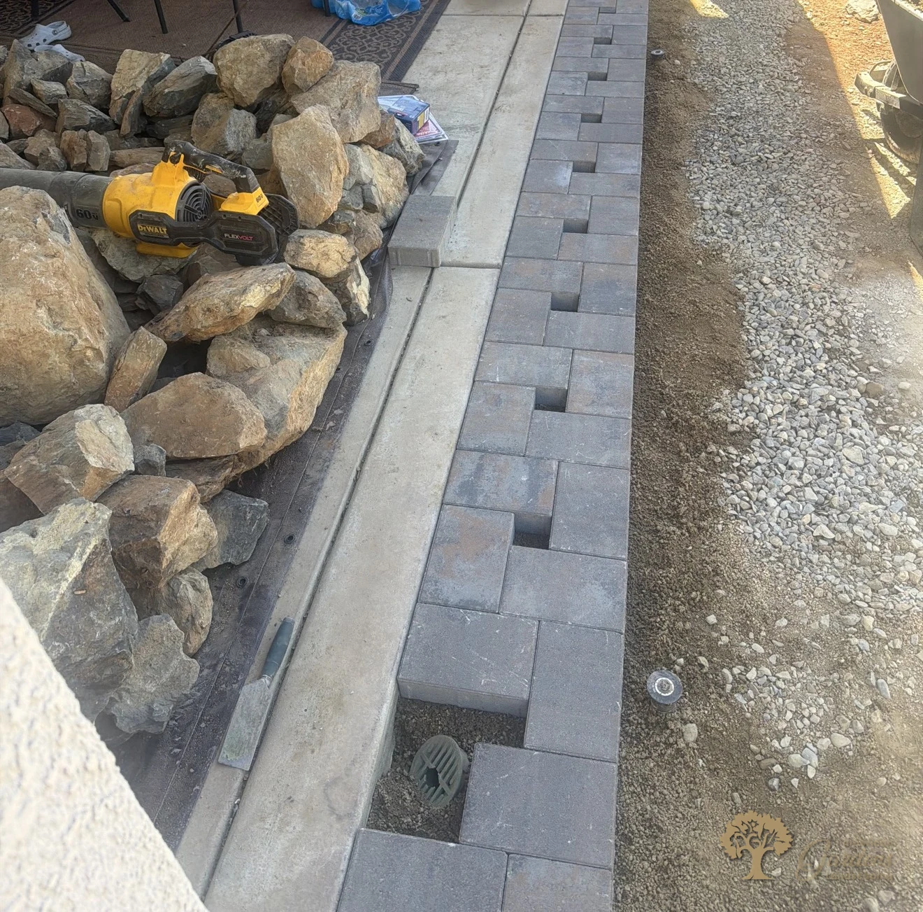 New paver walkway taking shape piece by piece beside the patio during a backyard build in El Dorado Hills, by American Gardens Landscaping.
