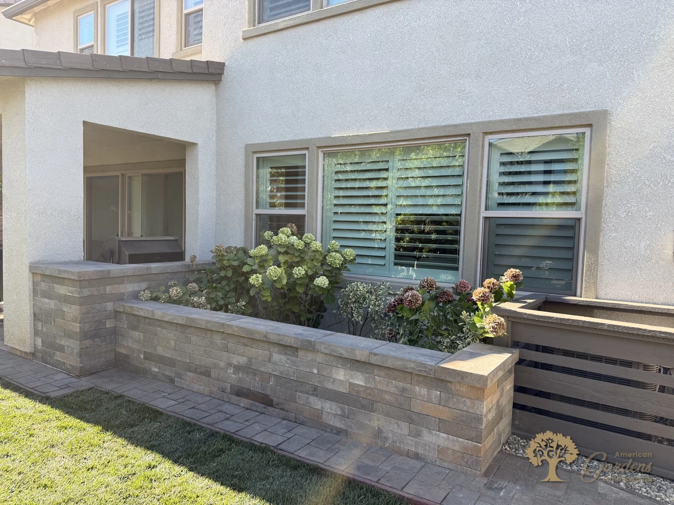 Raised block planter filled with hydrangeas between the patio and the screened AC enclosure, with the new lawn in front, in El Dorado Hills, by American Gardens Landscaping.