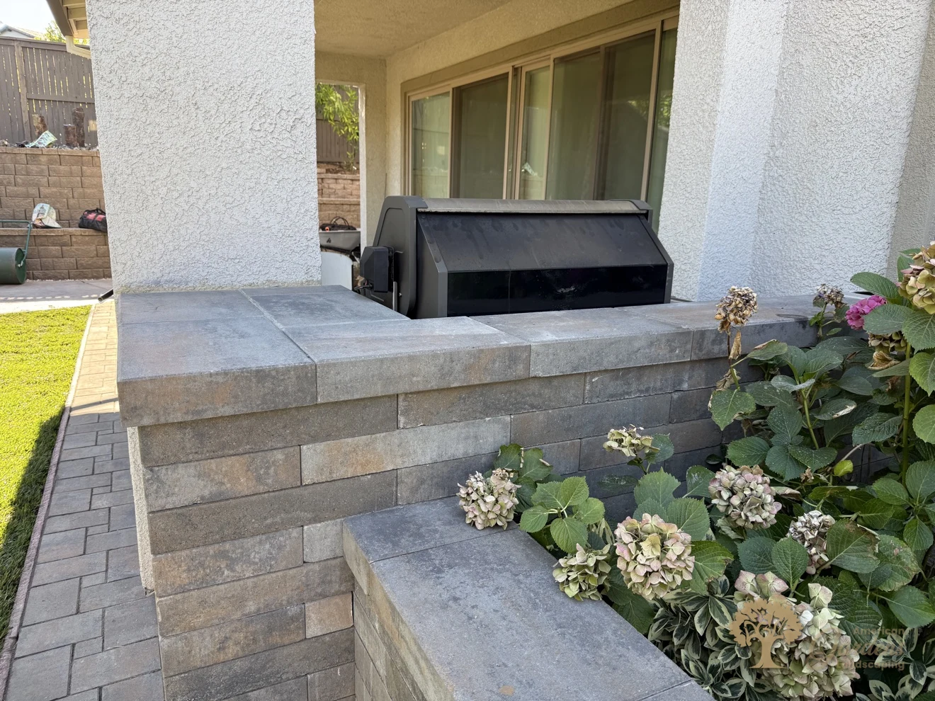 Close-up of the built-in grill set into the capped block planter wall beside the covered patio, with hydrangeas alongside, in El Dorado Hills, by American Gardens Landscaping.