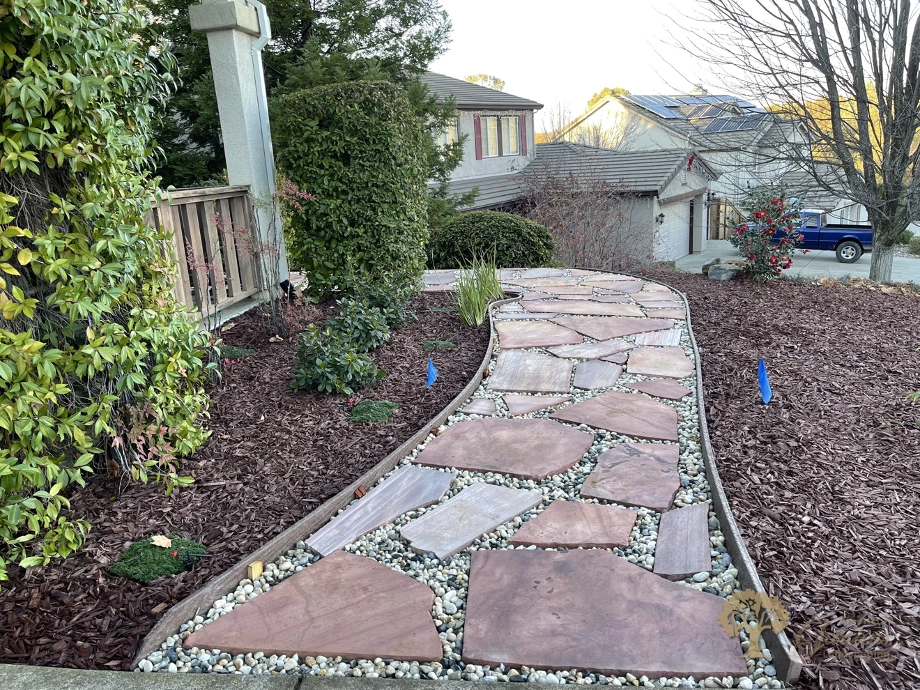 Natural flagstone walkway with river rock joints and bark mulch beds by American Gardens Landscaping