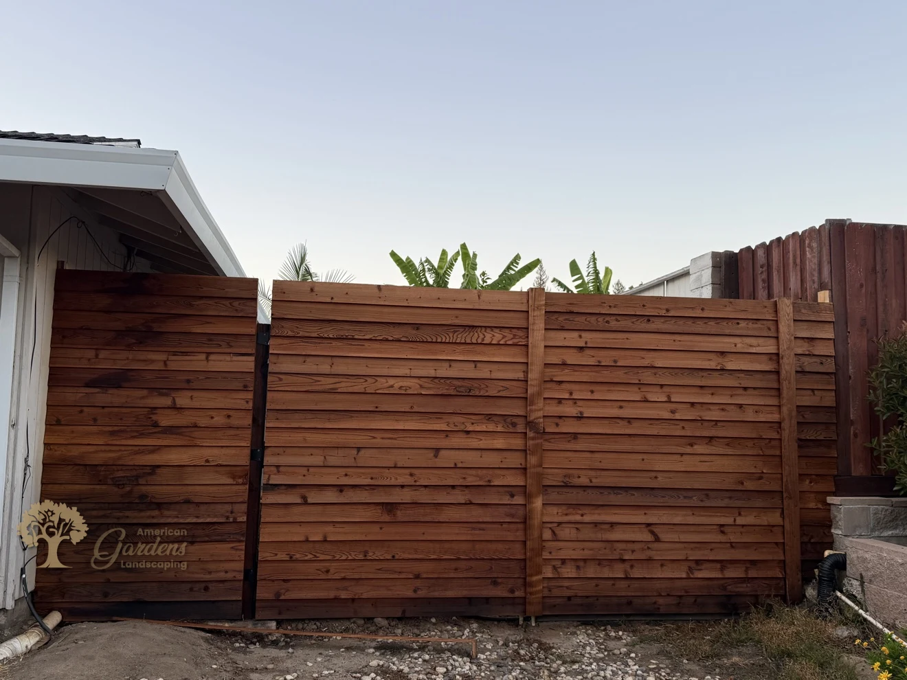 Horizontal redwood fence with a matching gate, built by American Gardens Landscaping