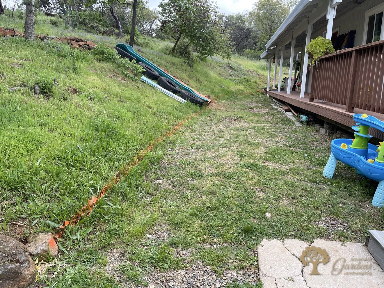 Grassy hillside with orange layout lines before a retaining wall build in Shingle Springs