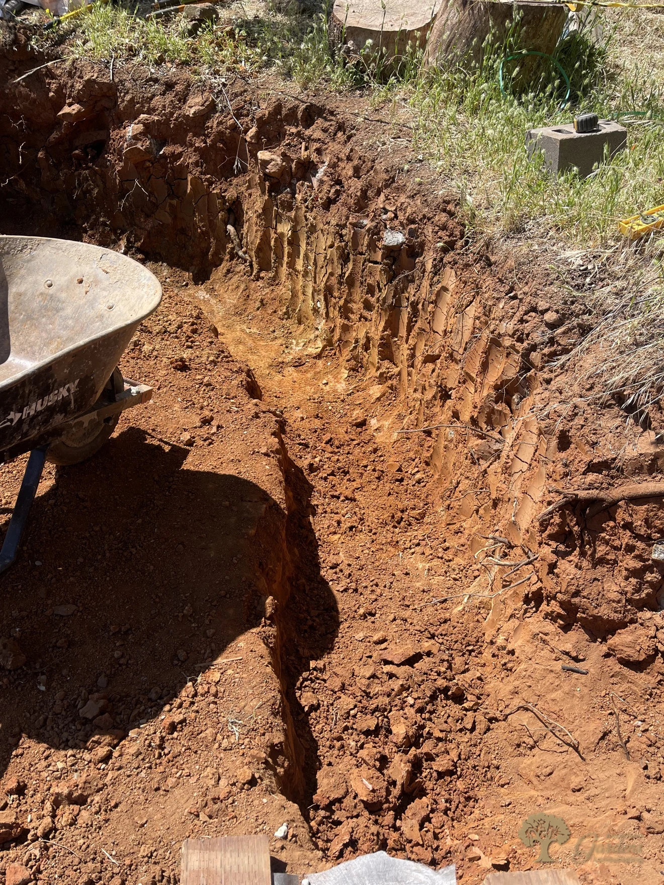 Excavated trench for a segmental block retaining wall in red rocky soil, Shingle Springs