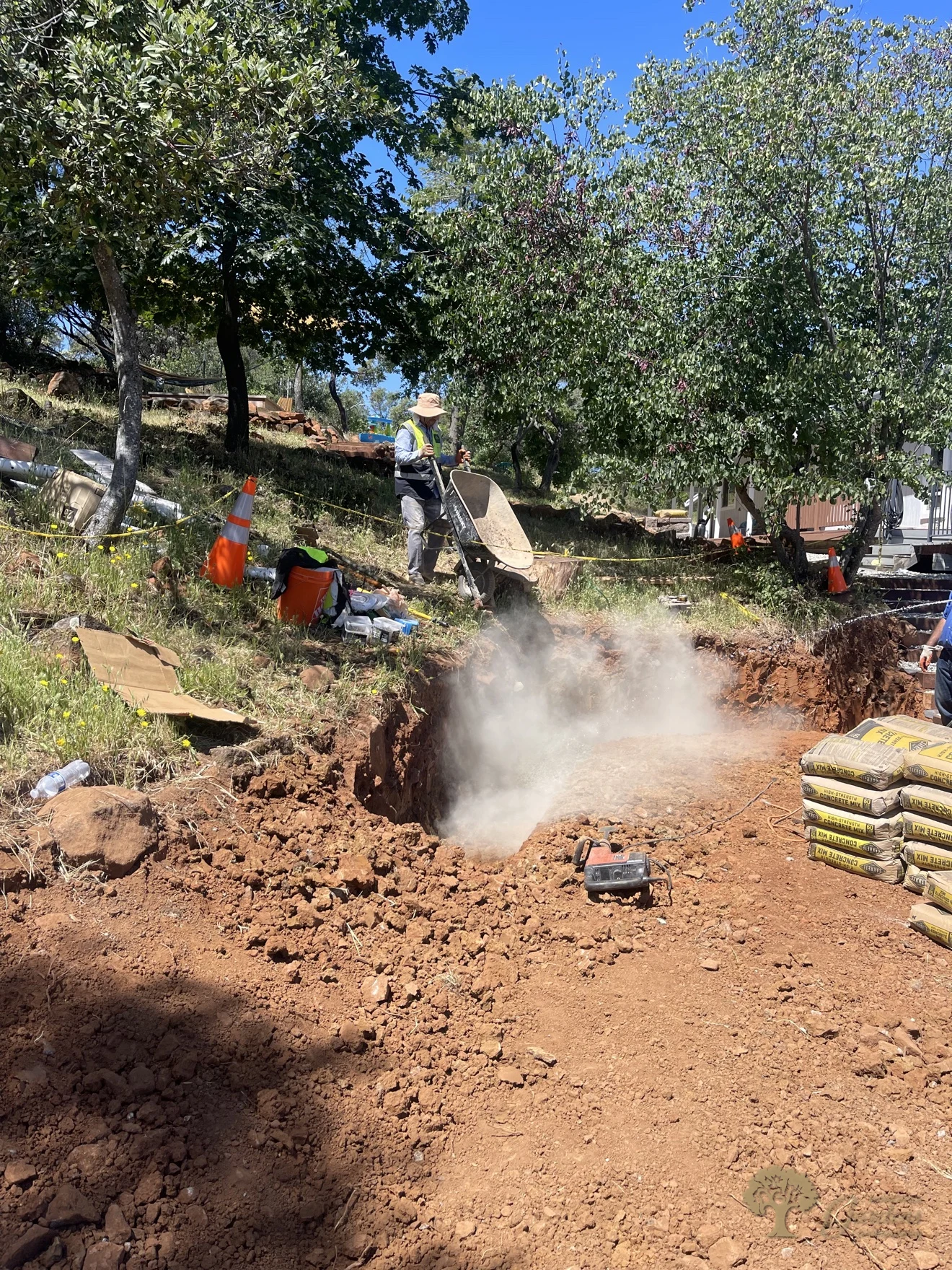 Wide view of a hillside retaining wall excavation with dust control in Shingle Springs