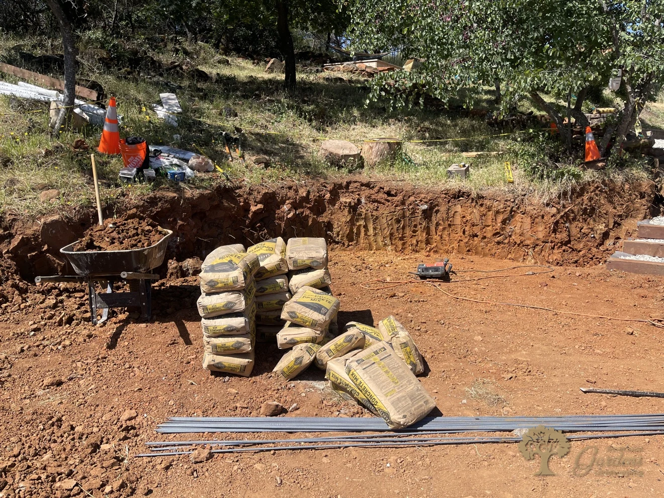 Concrete mix bags and rebar staged beside an excavated retaining wall trench in Shingle Springs