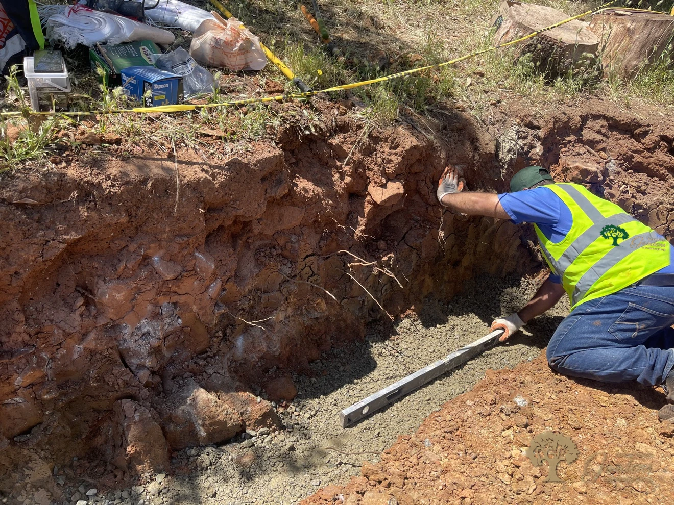 Worker leveling the gravel base of a segmental retaining wall in Shingle Springs