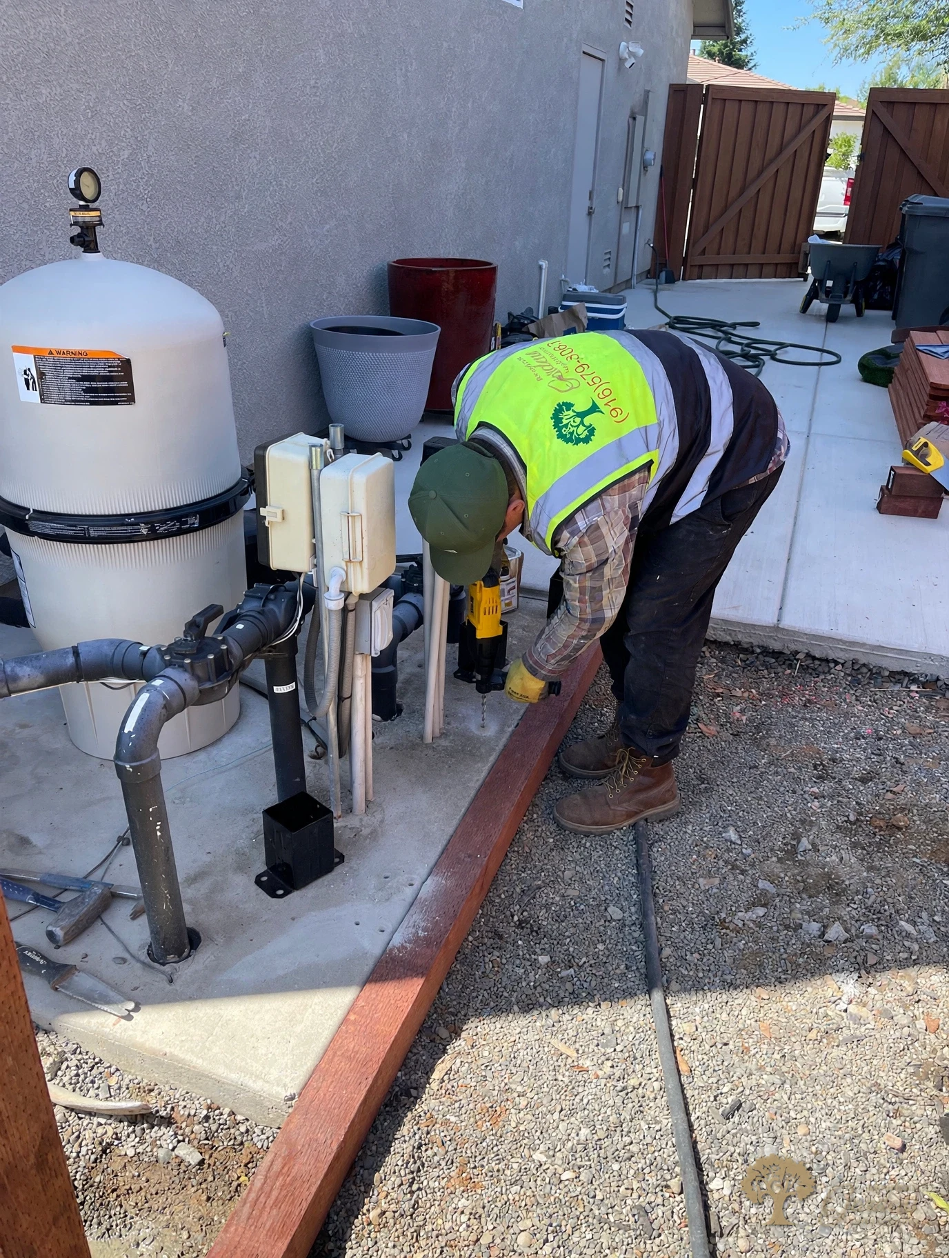 Drilling for Simpson post bases on the equipment pad in Rocklin – American Gardens Landscaping