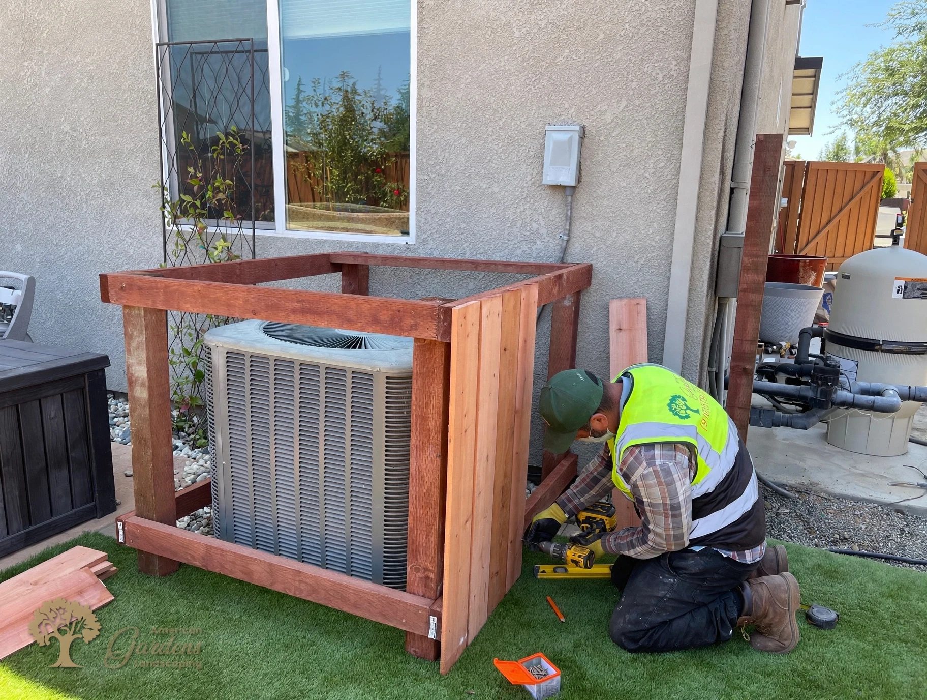 Screwing redwood pickets onto the AC enclosure frame in Rocklin – American Gardens Landscaping