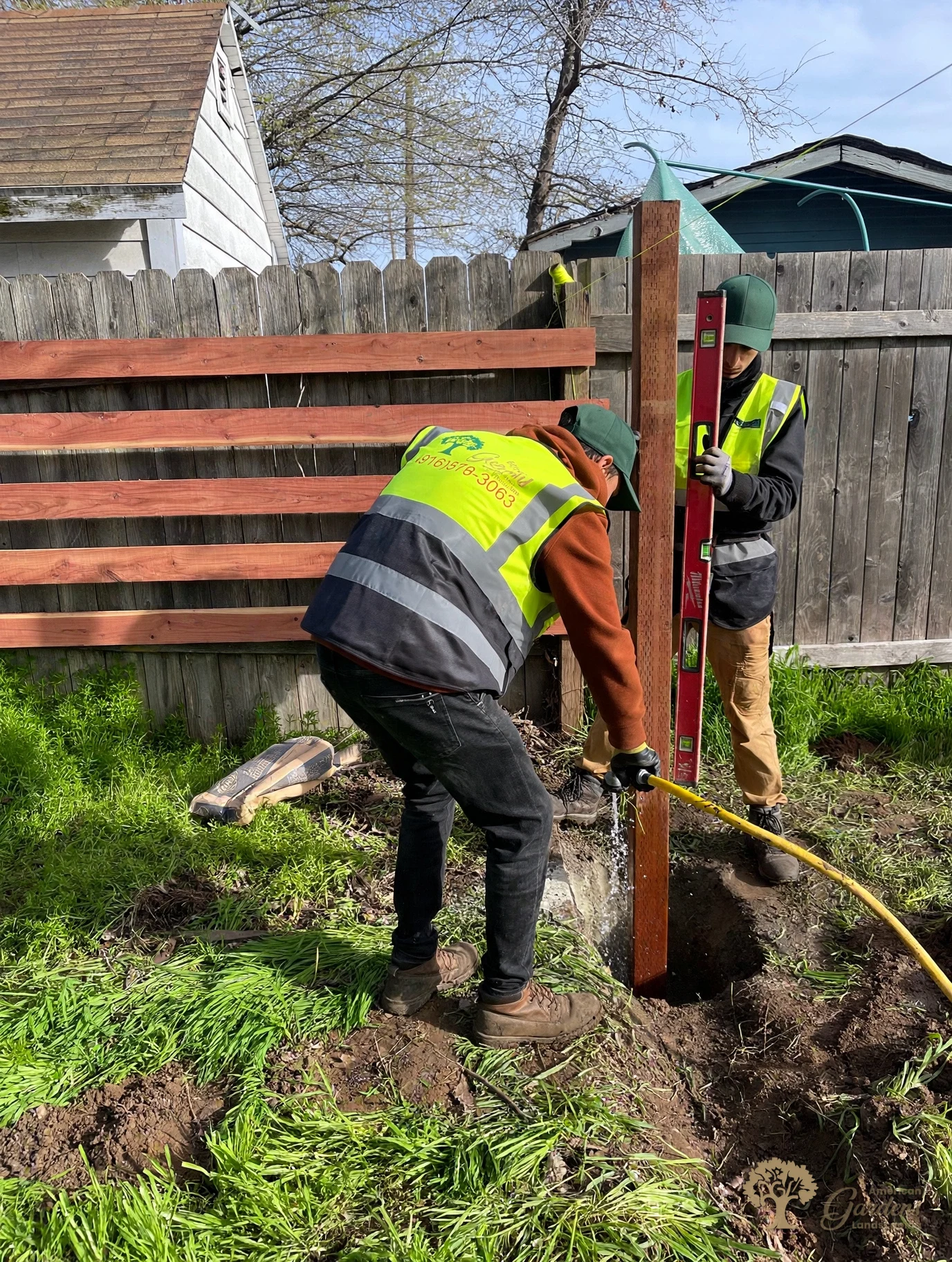 Worker installing redwood fence boards on a new fence by American Gardens Landscaping in Fair Oaks