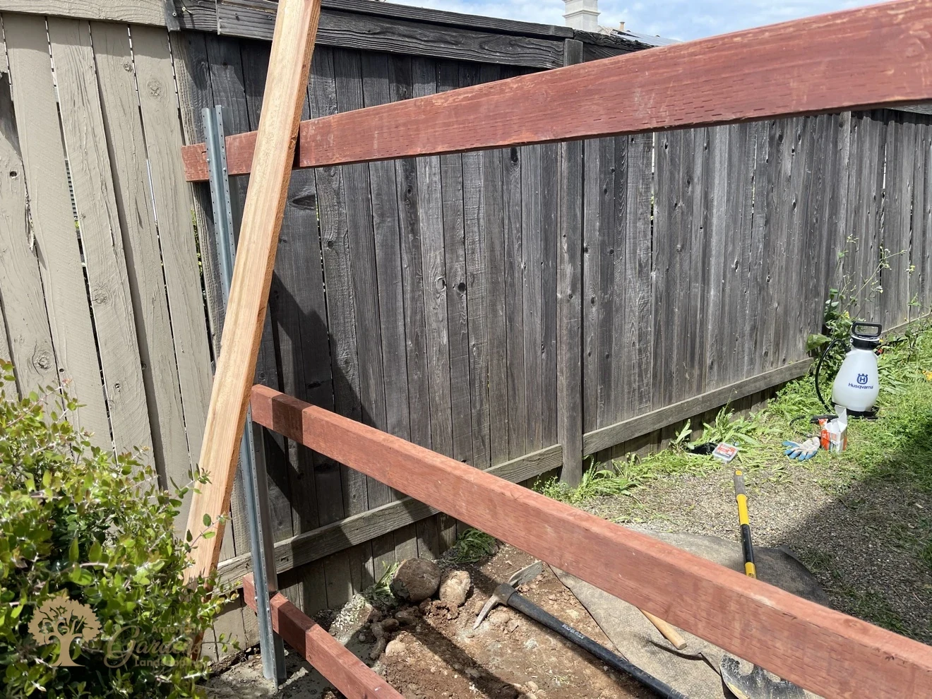 Pressure-treated rails mounted on galvanized steel posts with Simpson connectors in front of an old fence, during a redwood fence build in Roseville by American Gardens Landscaping