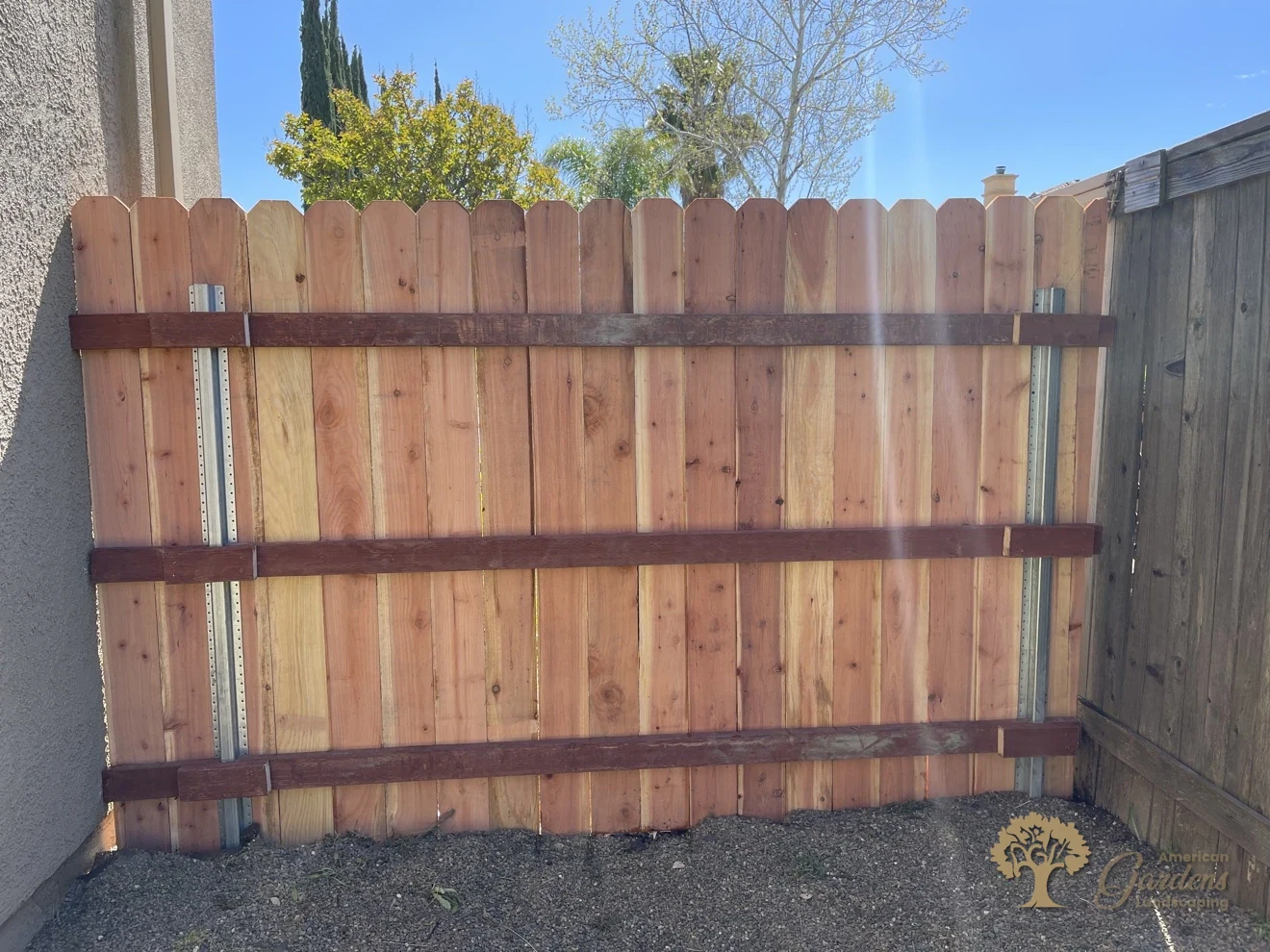 A finished section of redwood dog-ear fence on galvanized steel posts beside a house wall in Roseville, built by American Gardens Landscaping