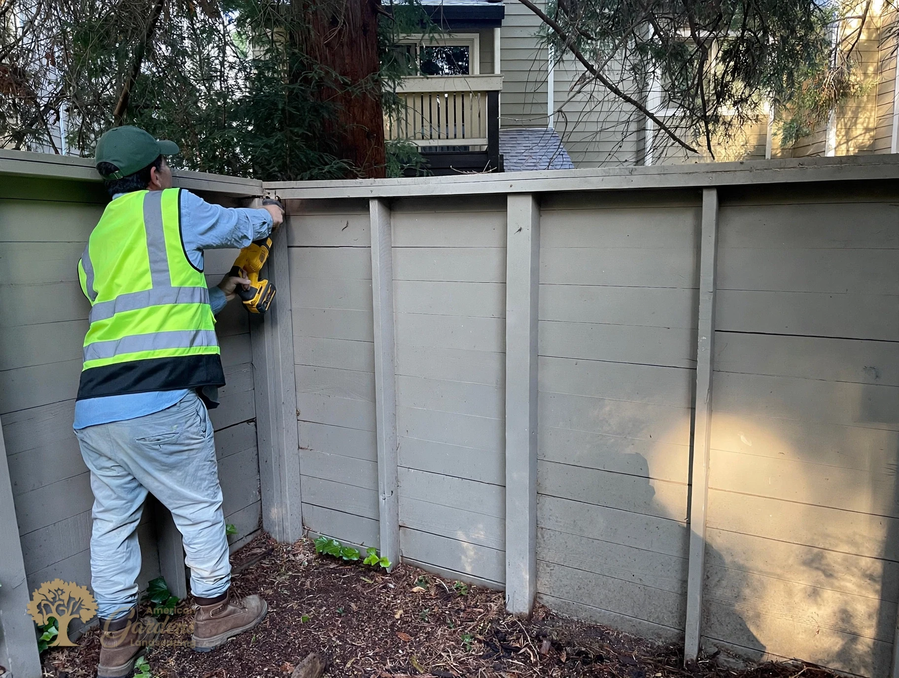 An American Gardens Landscaping crew member cutting the top rail of the old fence with a reciprocating saw during demolition in Sacramento