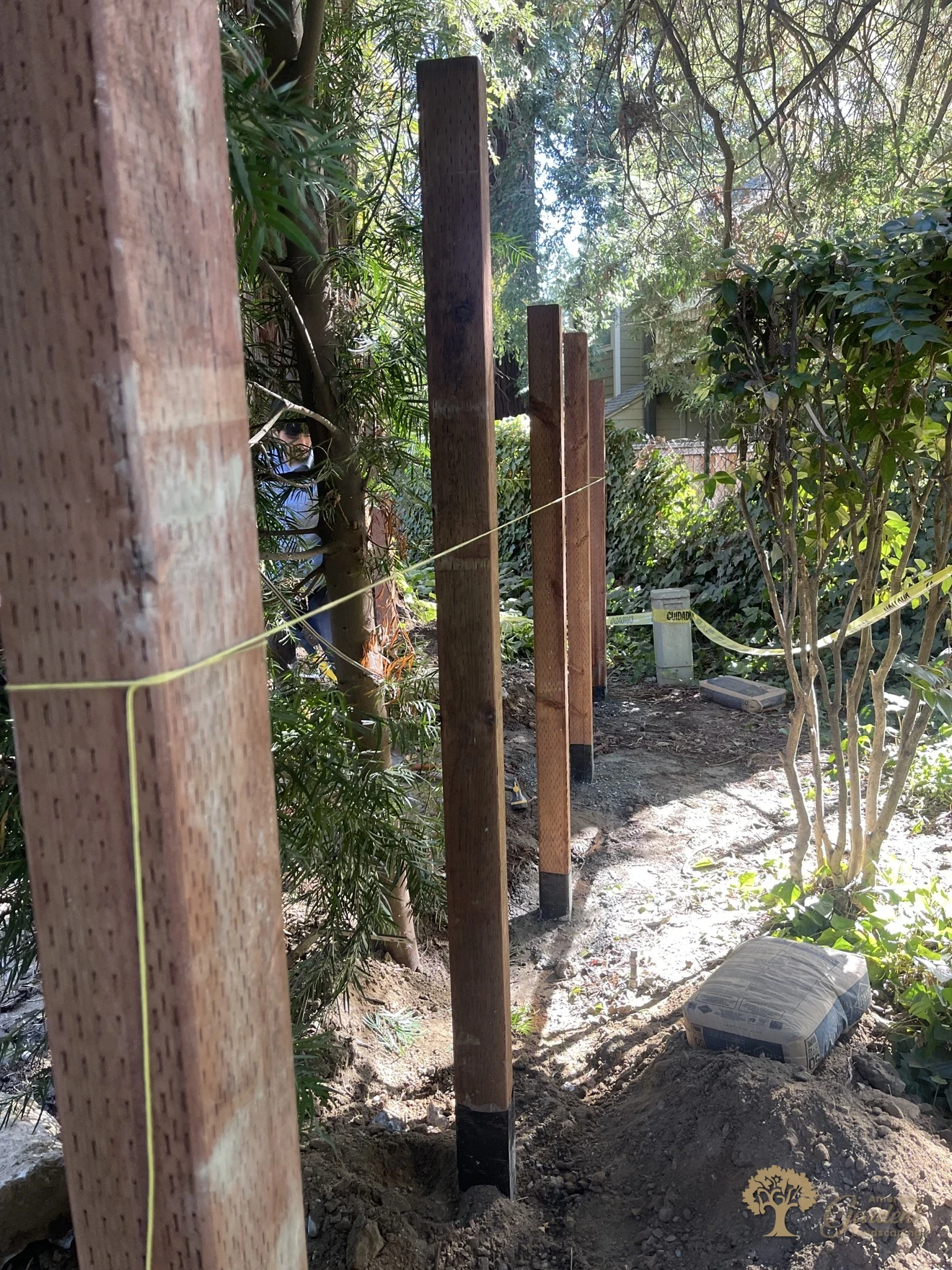 A line of new fence posts set on a string line in Sacramento, the black waterproof post wrap visible at each post bottom, by American Gardens Landscaping