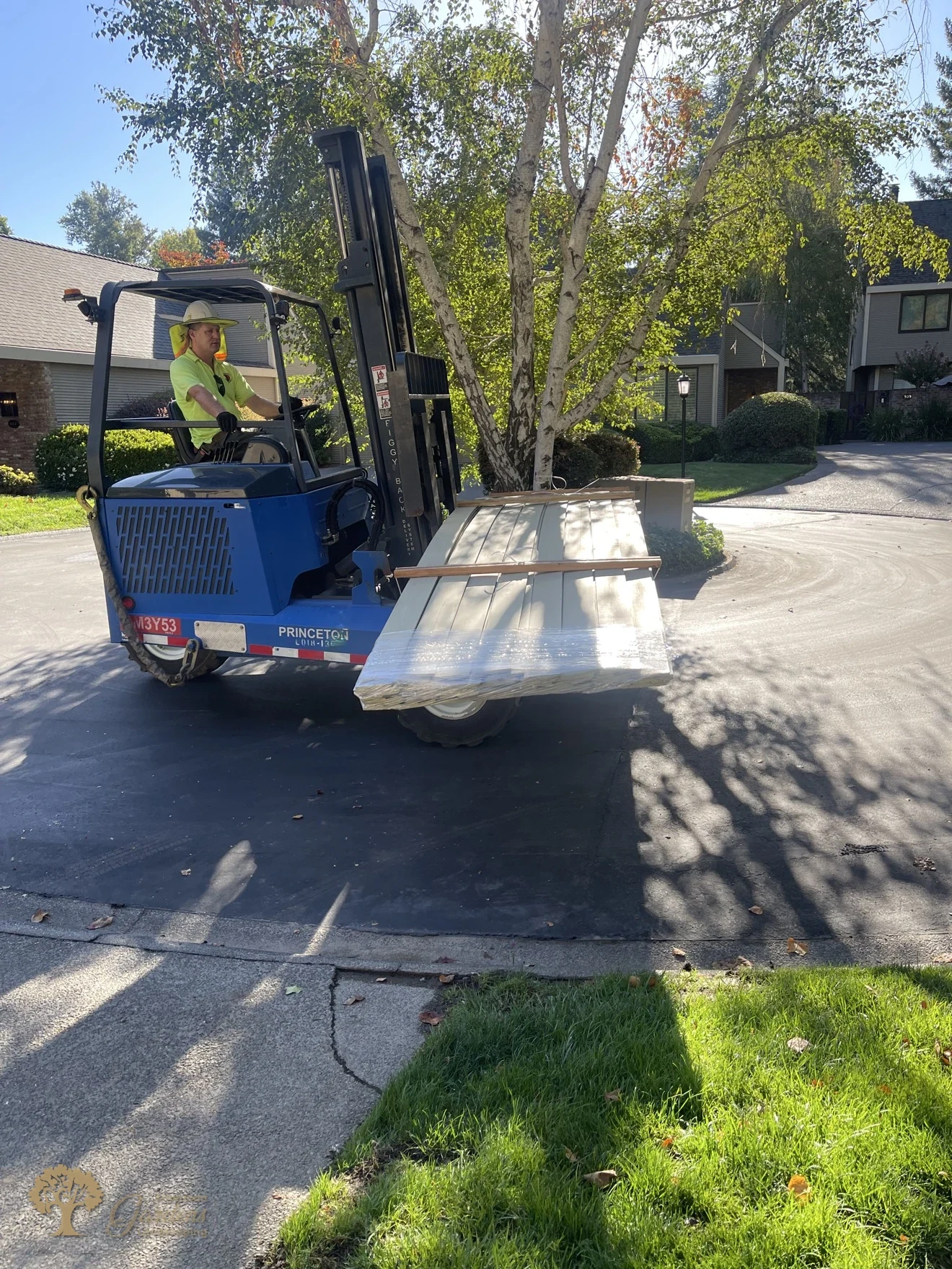 A forklift delivering a wrapped bundle of fence panels on the street of a Sacramento gated community for the fence replacement by American Gardens Landscaping