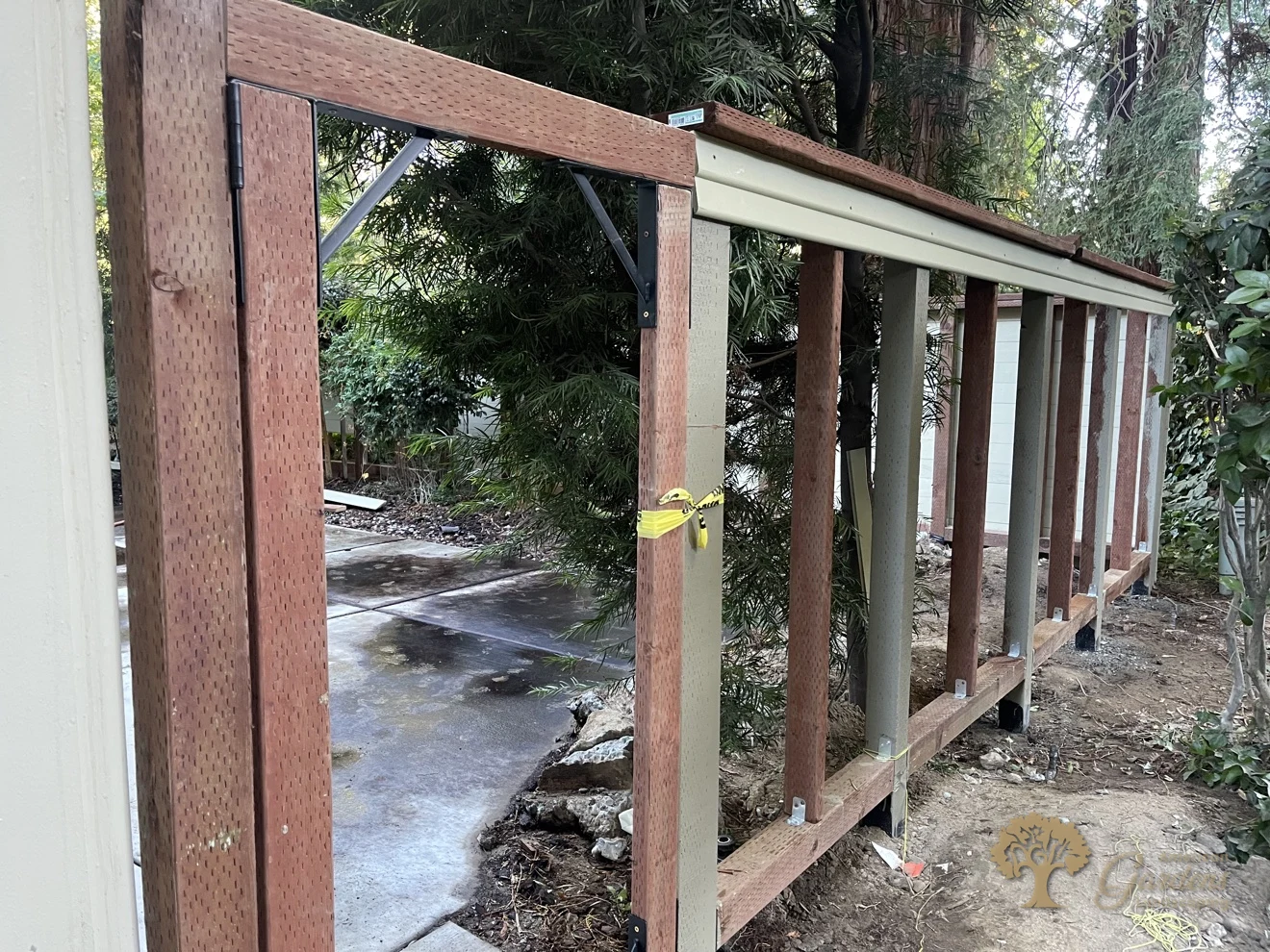 Gate frame detail with black steel gate brackets on a pressure-treated frame in Sacramento, with the new fence framing run behind it, by American Gardens Landscaping