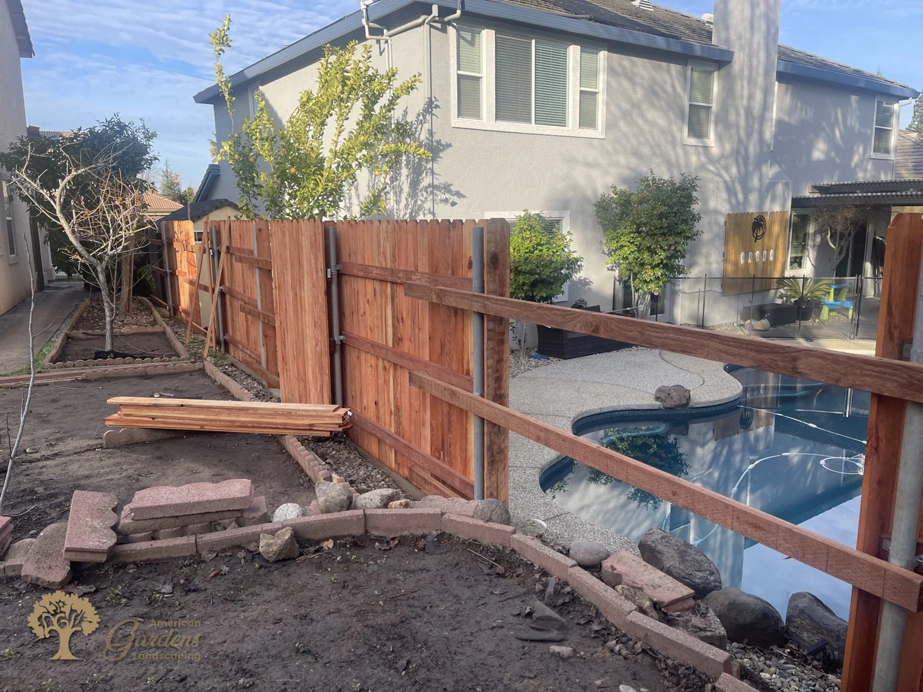 Redwood pickets going up on steel posts beside the pool in Folsom – American Gardens Landscaping