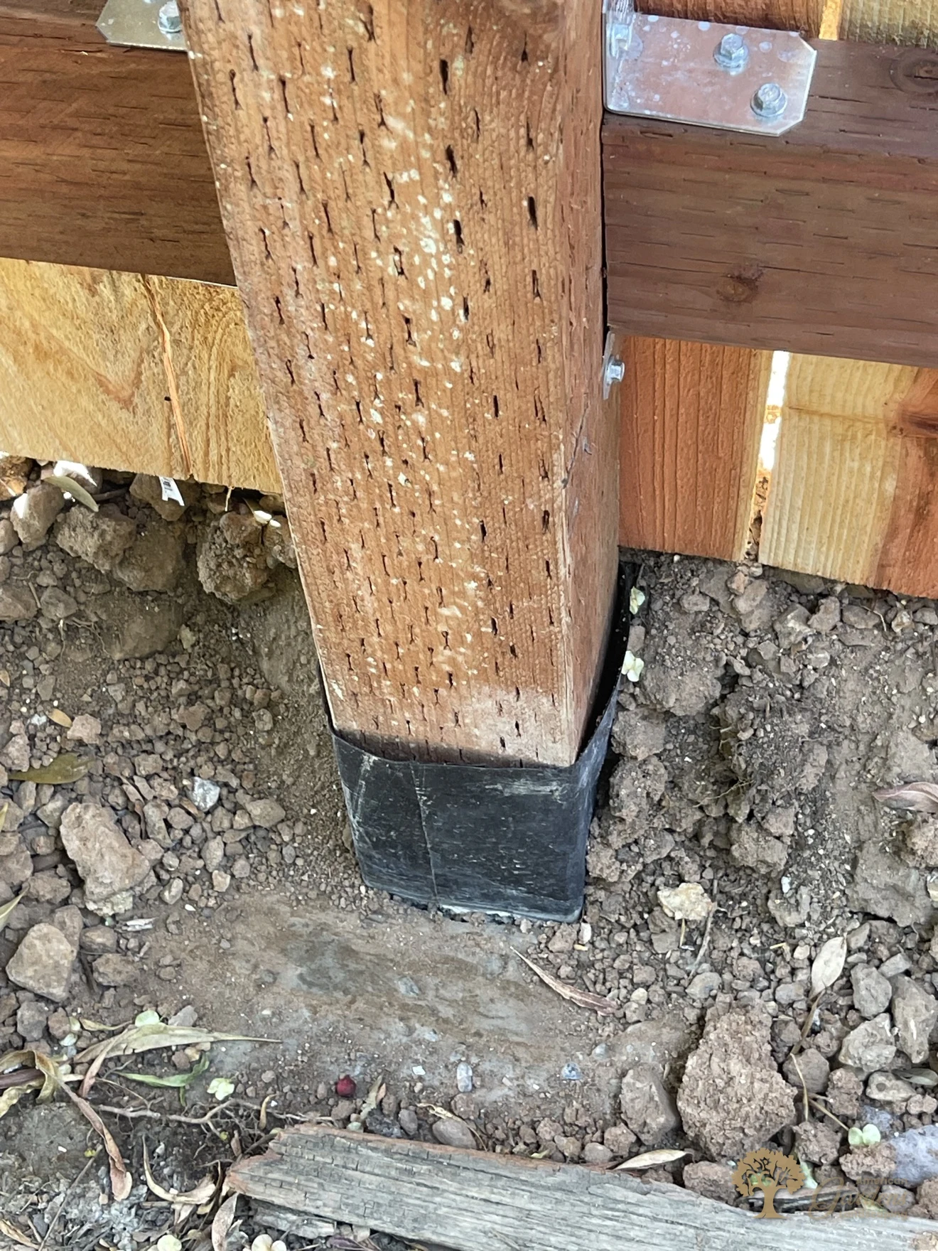 Waterproof post wrap and a Simpson bracket at the base of a pressure-treated post in Sacramento – American Gardens Landscaping