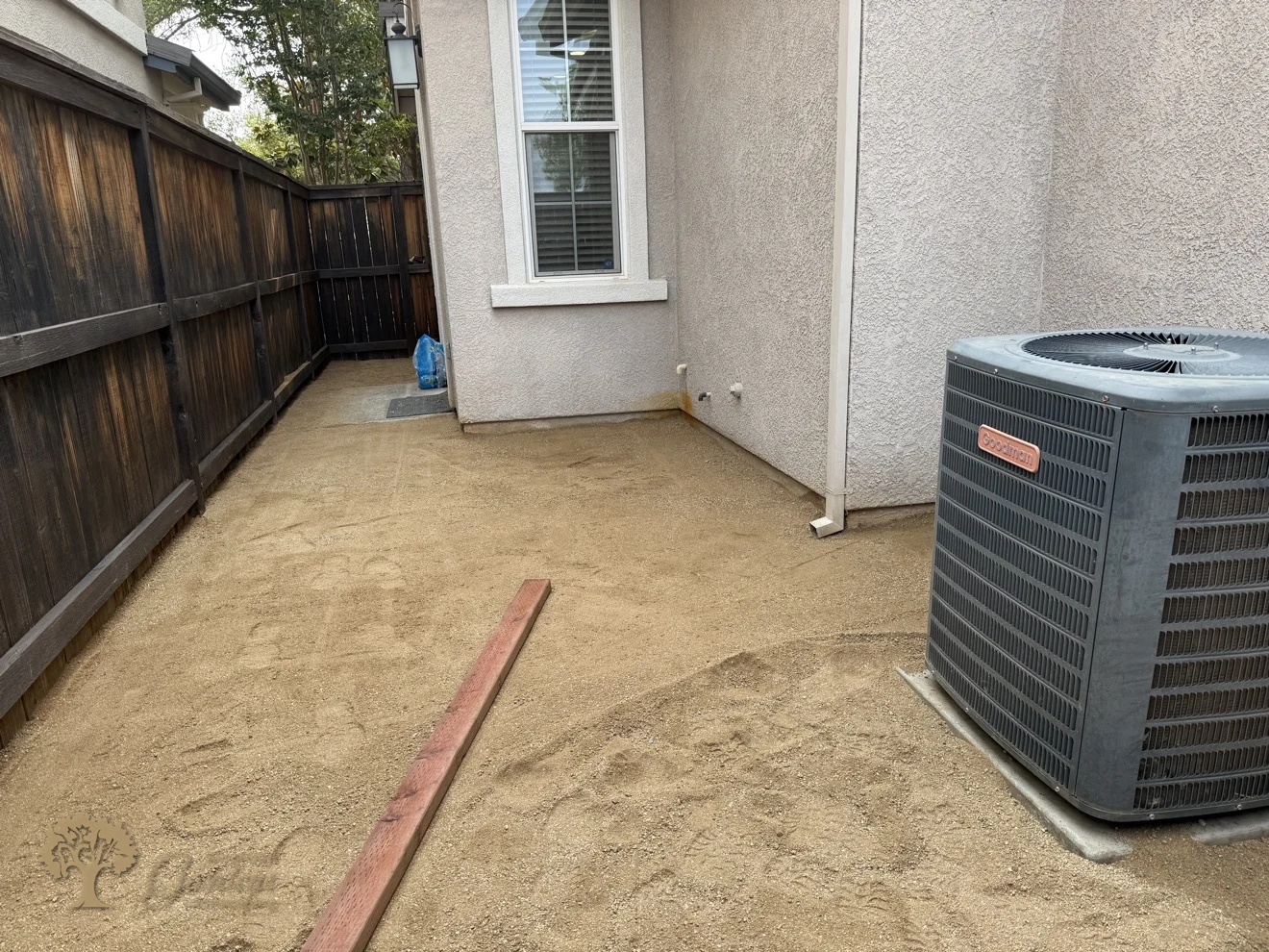 The compacted decomposed granite base leveled around the AC unit in a Rocklin side yard, ready for the new artificial turf by American Gardens Landscaping