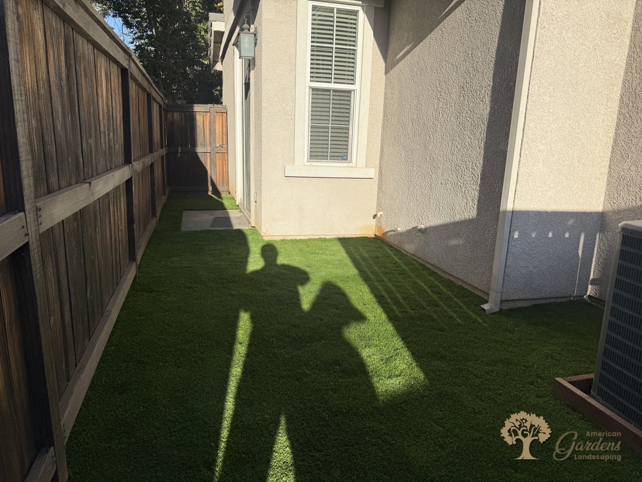 The finished artificial turf running down the narrow side-yard passage between the house and the wooden fence in Rocklin, by American Gardens Landscaping