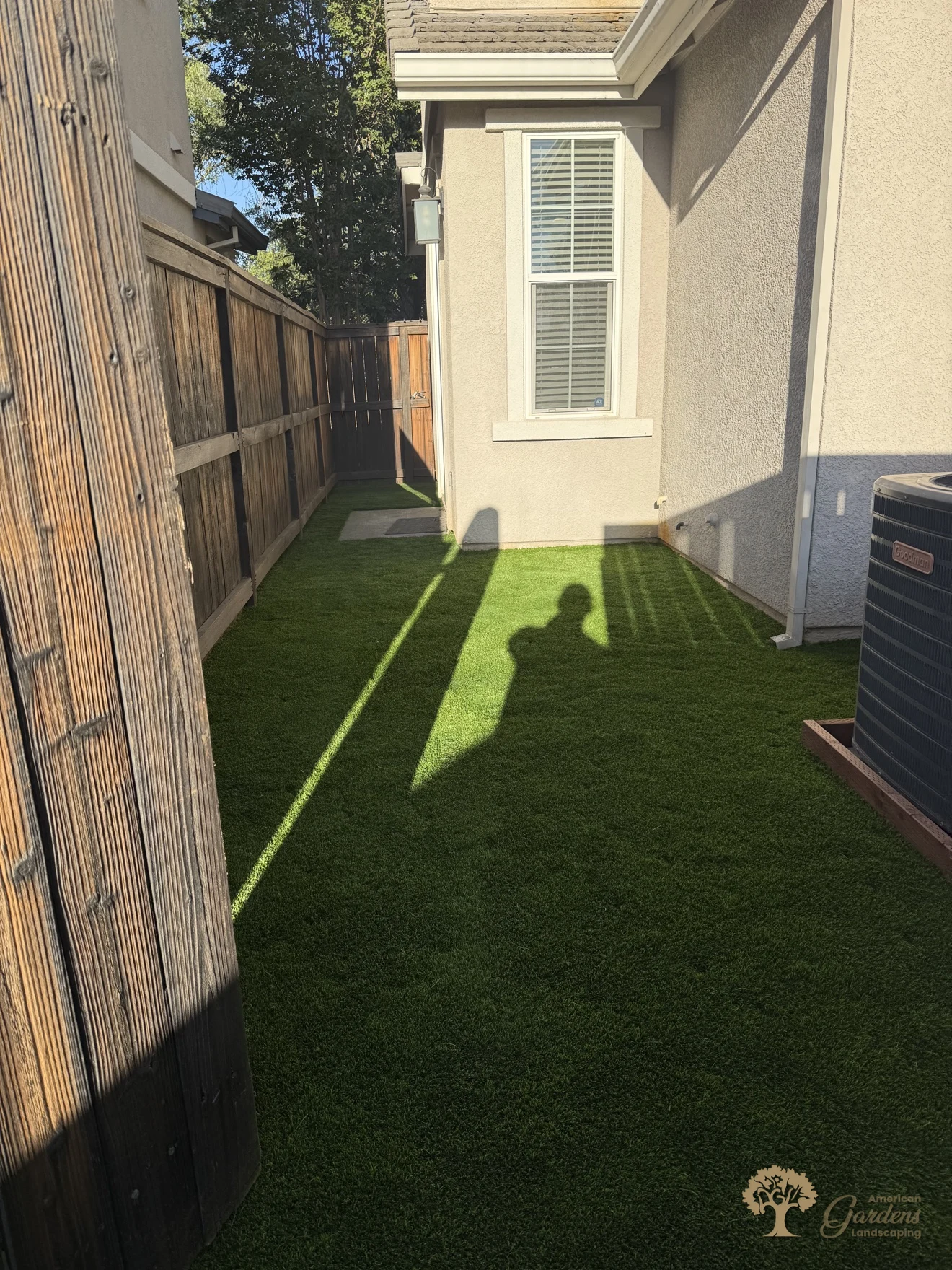 Looking into the finished artificial turf side yard from the gate post in Rocklin, with the AC unit at the far end, by American Gardens Landscaping