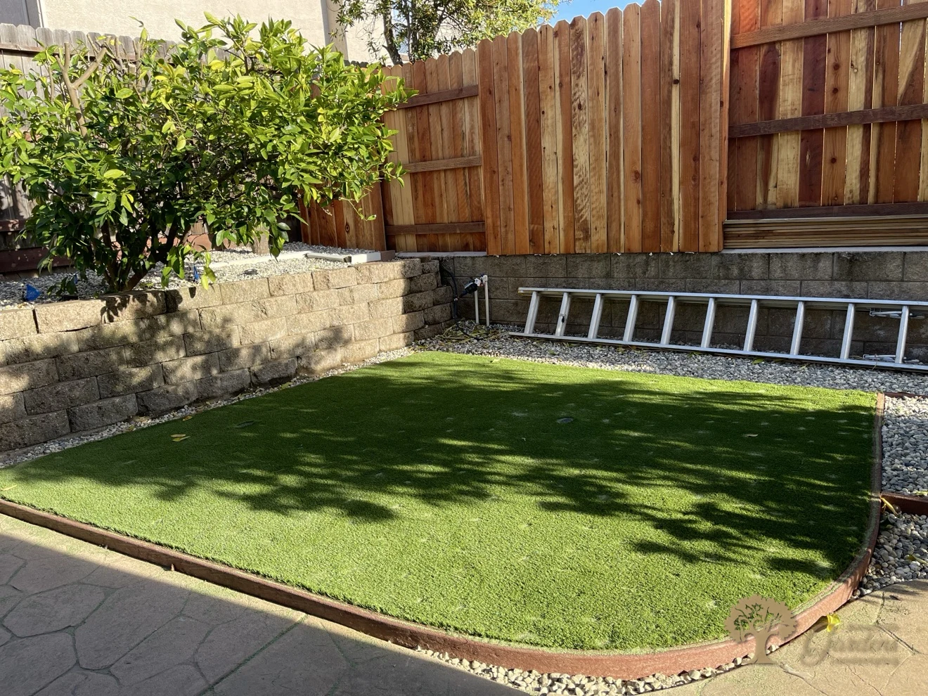 Finished artificial grass corner by the cleaned block wall and stained redwood fence in Folsom – American Gardens Landscaping
