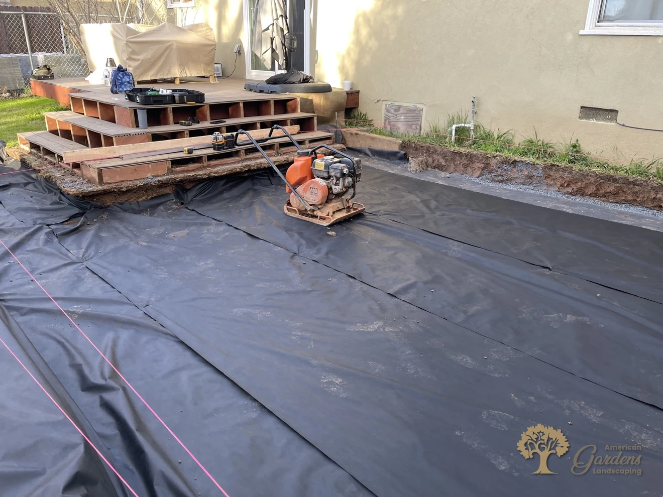 Geotextile fabric laid over excavated soil for a herringbone paver patio in Sacramento – American Gardens Landscaping