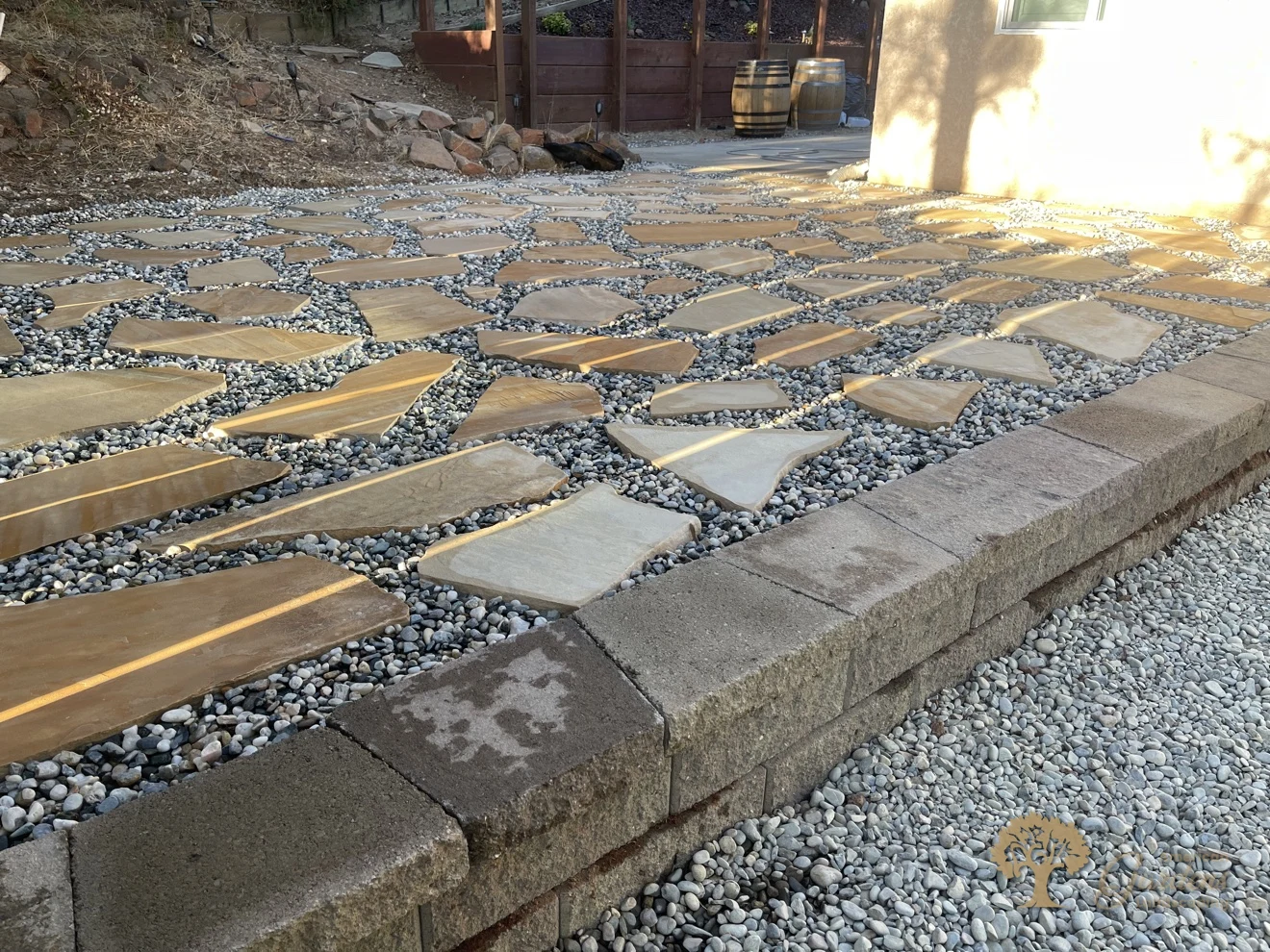 A close detail of the warm-tan flagstone patio with pebble joints and a stone edge course in Shingle Springs, by American Gardens Landscaping