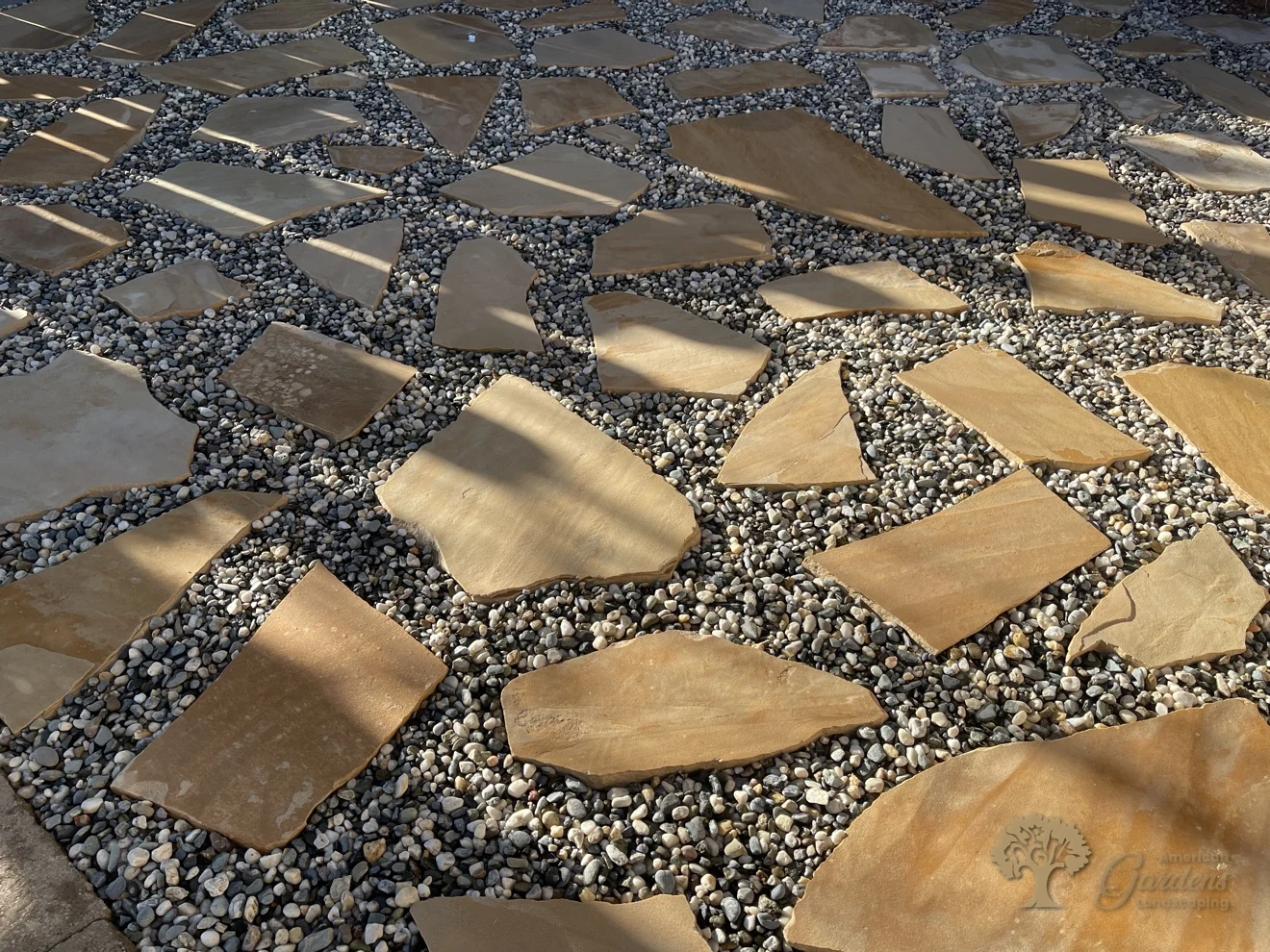 A close-up of the warm-tan flagstones and pebble joints of the finished patio in Shingle Springs, by American Gardens Landscaping